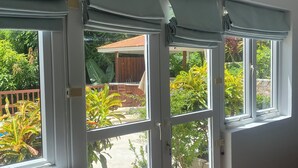 A room with large windows, a wooden floor, and a view of a garden. - Fabulous poolside apartment Marigot Bay. (Marigot bay)