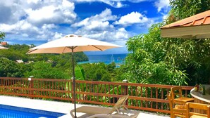 A poolside area with lounge chairs, a table, and an umbrella. - Fabulous poolside apartment Marigot Bay. (Marigot bay)