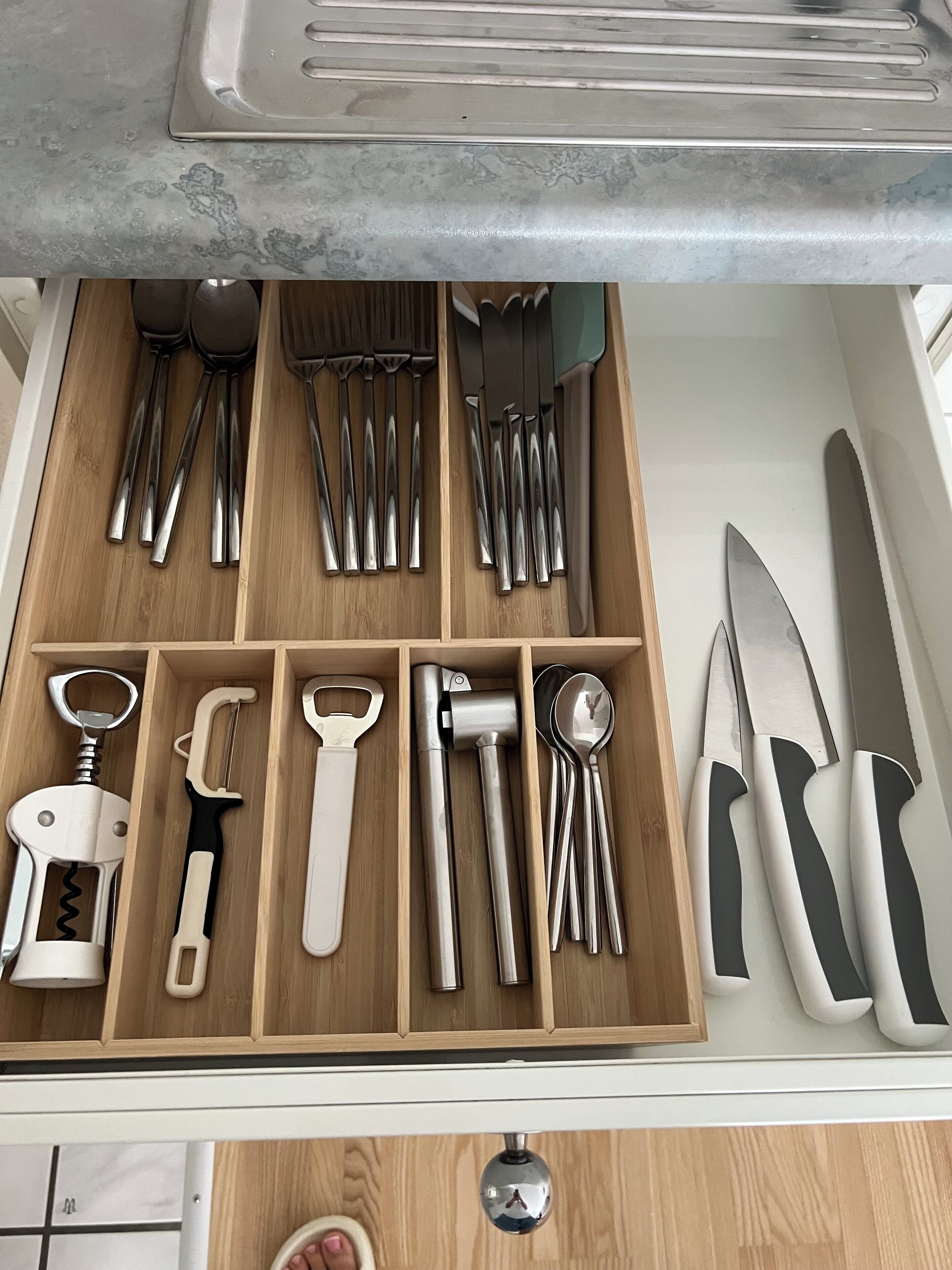 A drawer with various kitchen utensils organized in compartments.