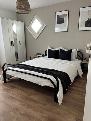 Une chambre à coucher comprenant un lit, une armoire, un bureau et un luminaire suspendu.