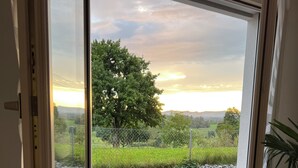A room with a large window offering a view of a tree and a fence. - Black & White Apartment (Bichwil)