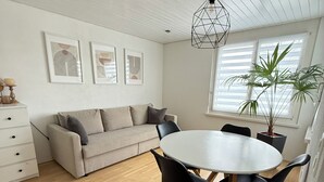 A modern living space with a sofa, dining table, chairs, and artwork on the walls. - Black & White Apartment (Bichwil)