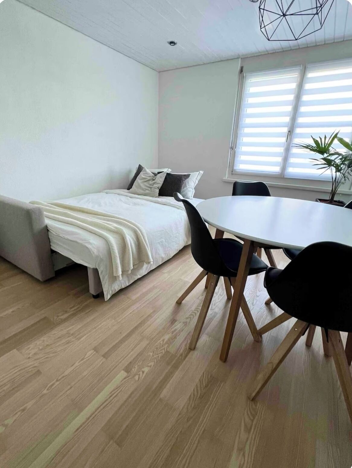 Una habitación pequeña con cama, mesa de comedor y sillas.