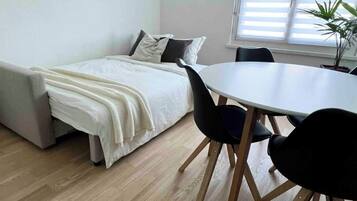 Una habitación pequeña con cama, mesa de comedor y sillas.