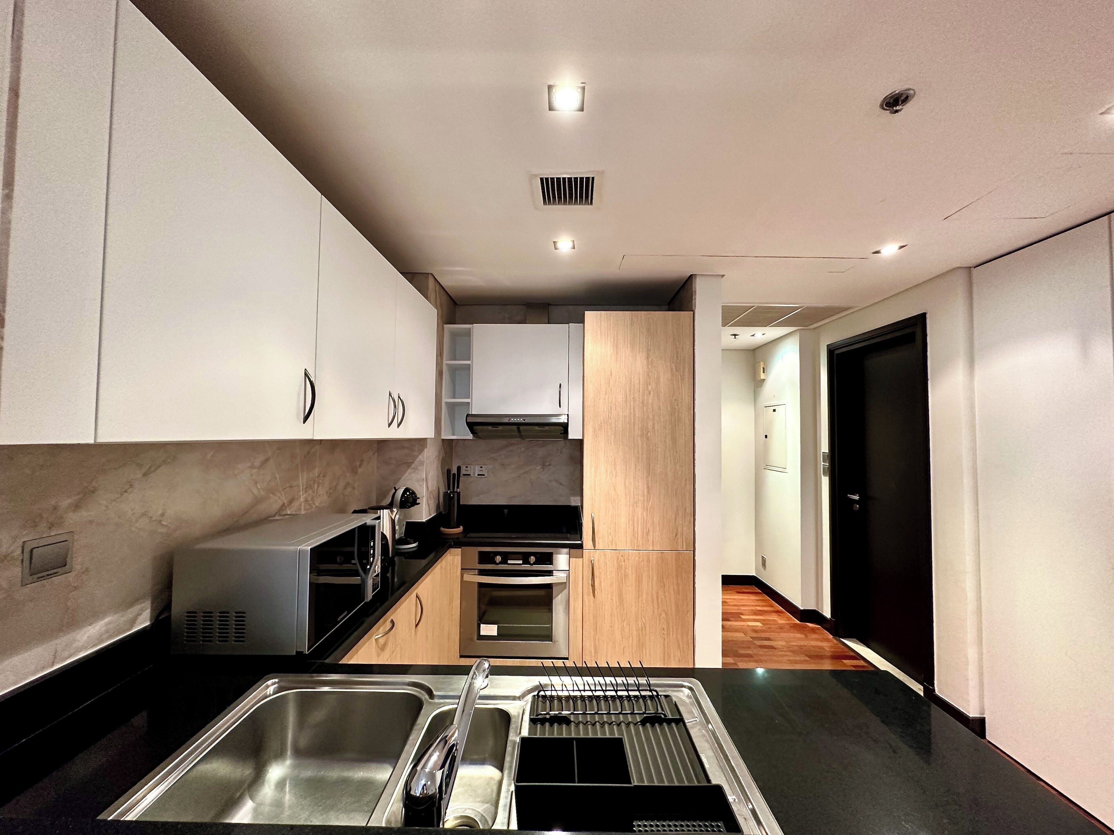A modern kitchen with stainless steel appliances, wooden cabinets, and a black countertop.