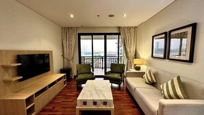 A living room with a flat-screen TV, a sofa, a coffee table, and a balcony with a view. - Lux BnB I Palm Jumeirah Resort I Palm Views (Dubai)