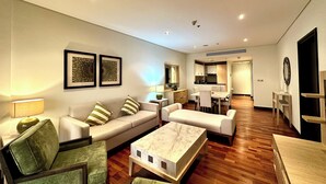 A modern living room with a sofa, chairs, a coffee table, and a dining area with a kitchen in the background. - Lux BnB I Palm Jumeirah Resort I Palm Views (Dubai)