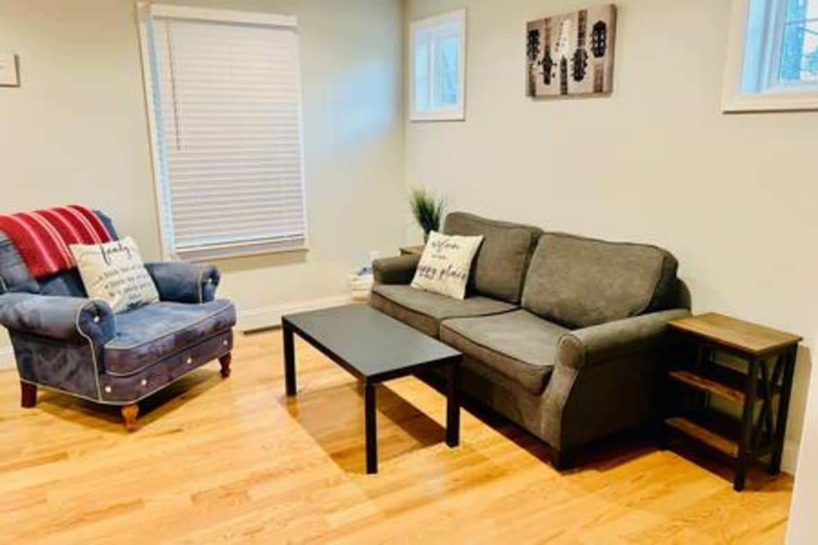 A living room with a sofa, armchair, coffee table, and side table.