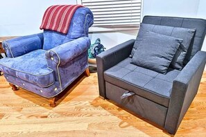 A room with a blue armchair and a grey sofa.