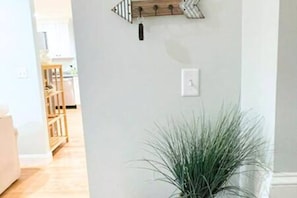 A room with a wooden floor, a white wall, and a potted plant.