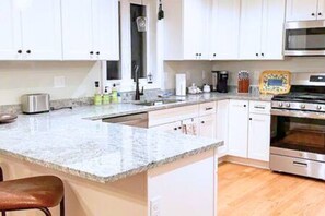 A kitchen with white cabinets, a granite countertop, a stainless steel oven, and a microwave.
