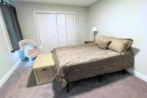 A bedroom with a bed, a chair, a lamp, and a wardrobe.