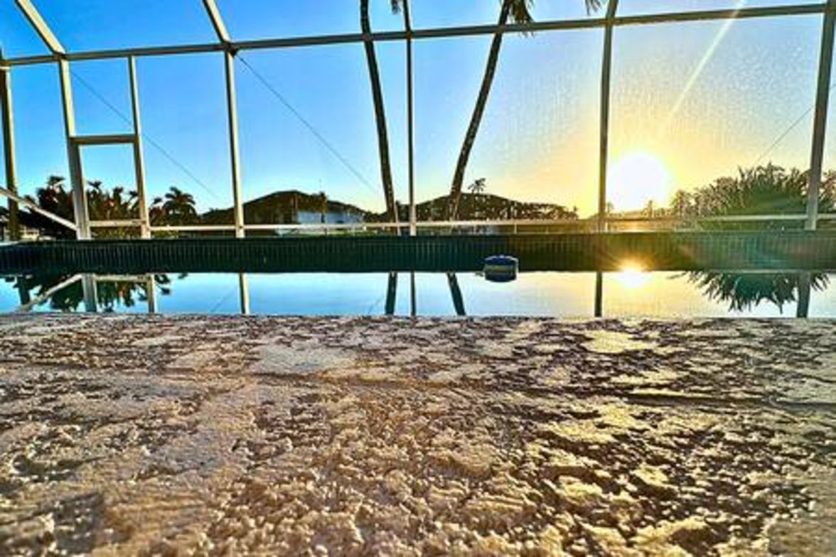 Una piscina interior con paredes de vidrio transparente, vistas al exterior y una superficie de agua tranquila.