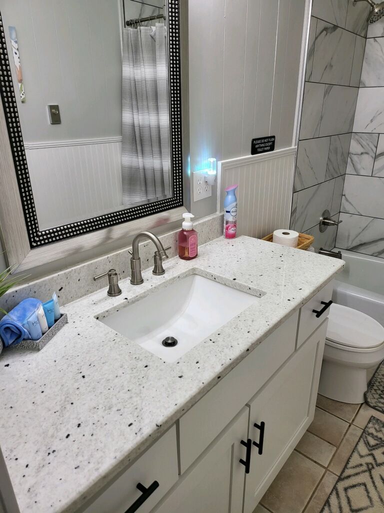 Ein Badezimmer mit einem weißen Waschbecken, einem Spiegel mit LED-Beleuchtung, einer Duschkabine mit Glastür und einer Toilette.