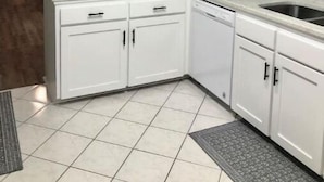 Uma cozinha compacta com armários brancos, pia embutida e um pequeno espaço de refeições com mesa e cadeira.