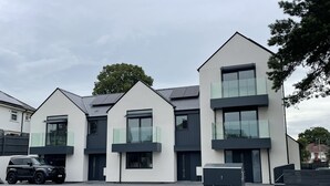 A modern residential building with a flat roof, large windows, and a minimalist design.