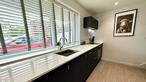 A modern kitchen with a large window, black cabinets, and a wooden floor.