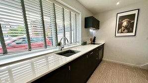 A modern kitchen with a large window, black cabinets, and a wooden floor. - Stunning Brand New House - Sleeps 6 - Free Parking (Poole)