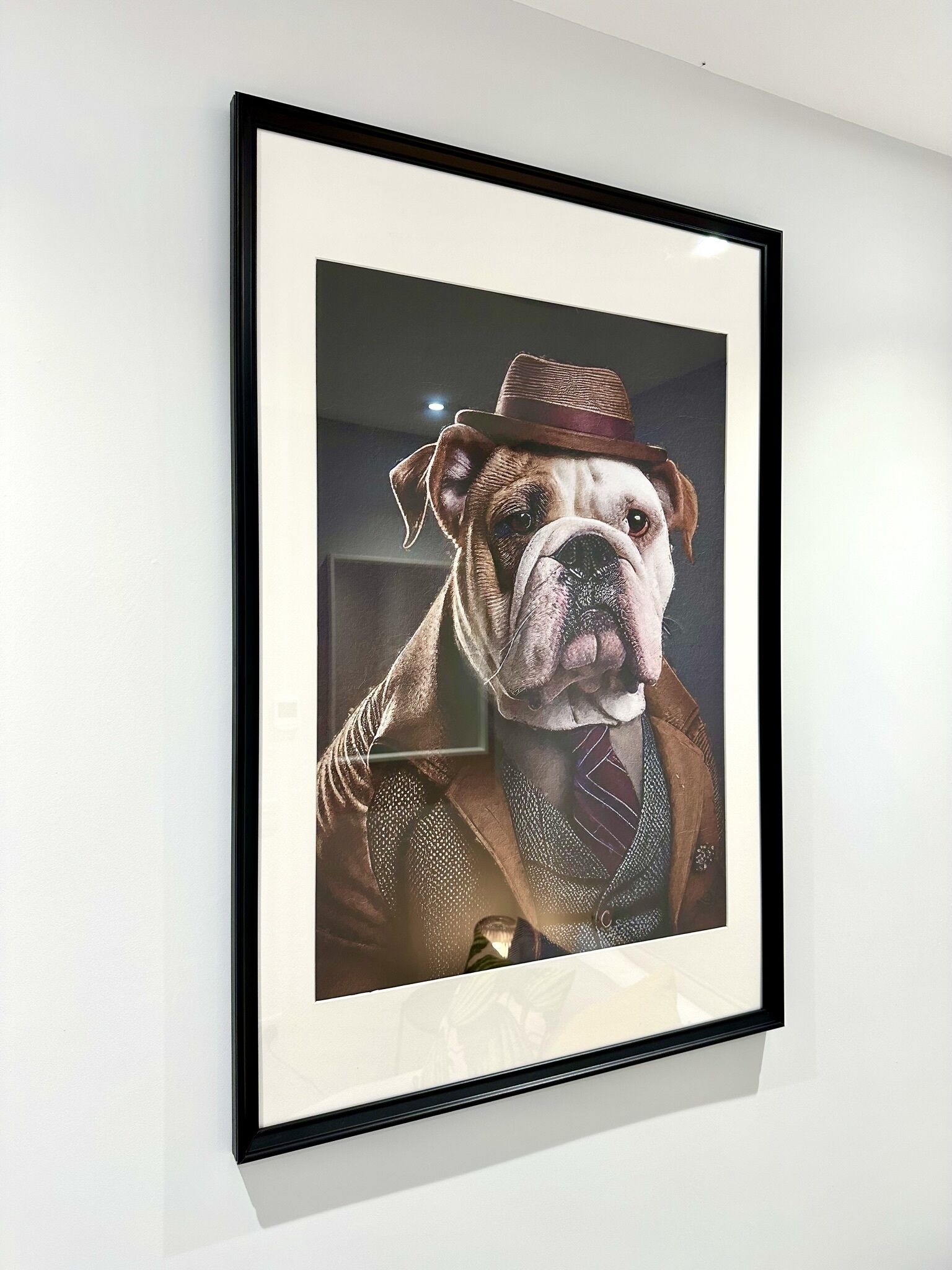 A framed portrait of a dog in a suit and hat.