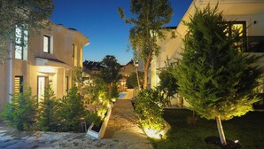 Una zona residencial con senderos de piedra, árboles bien iluminados y casas modernas.