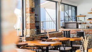 Un restaurante con paredes de ladrillo, ventanas amplias y mesas y sillas de madera.
