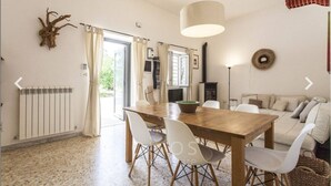 Uma área de refeições com mesa e cadeiras de madeira, um radiador e vista para o exterior.