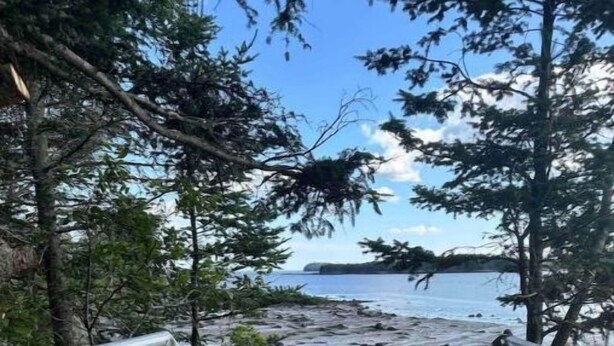 Unes escales de fusta amb baranes metàl·liques que baixen fins a una zona de platja rocosa.
