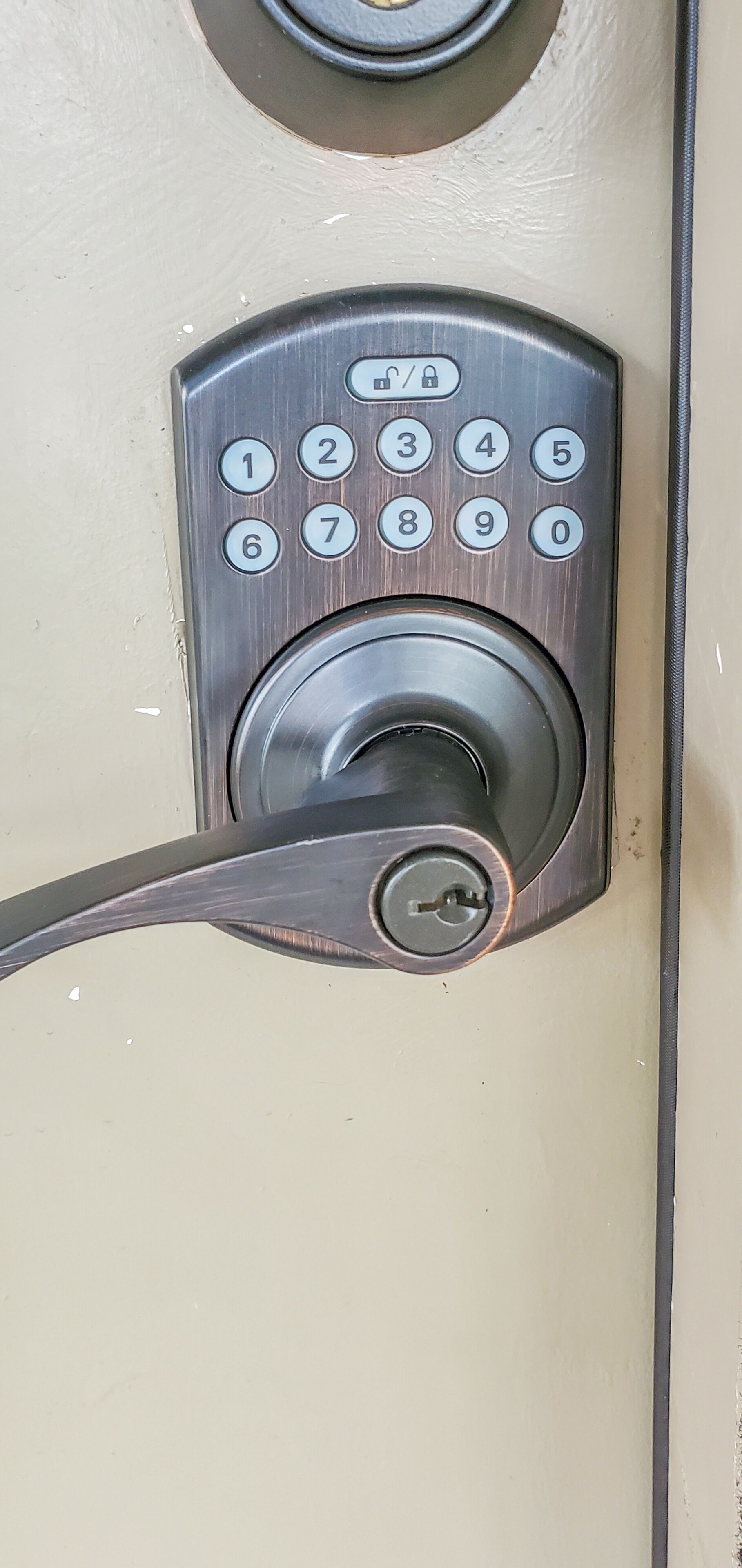 A close-up of a door lock with a numeric keypad and a keyhole.