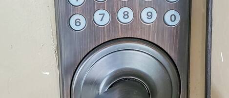 A close-up of a door lock with a numeric keypad and a keyhole.