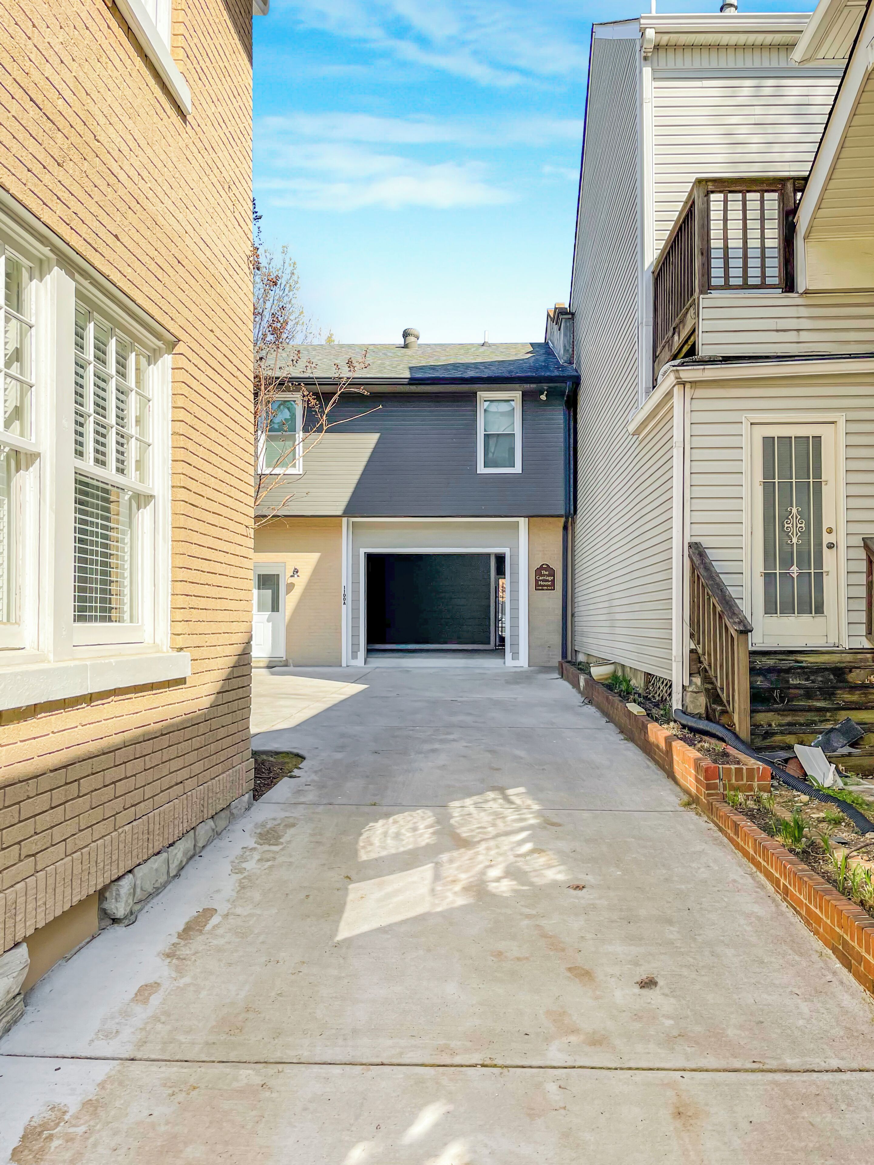 A residential driveway leading to a garage, with a brick wall on the left and a wooden fence on the right.
