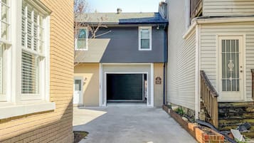 A residential driveway leading to a garage, with a brick wall on the left and a wooden fence on the right.