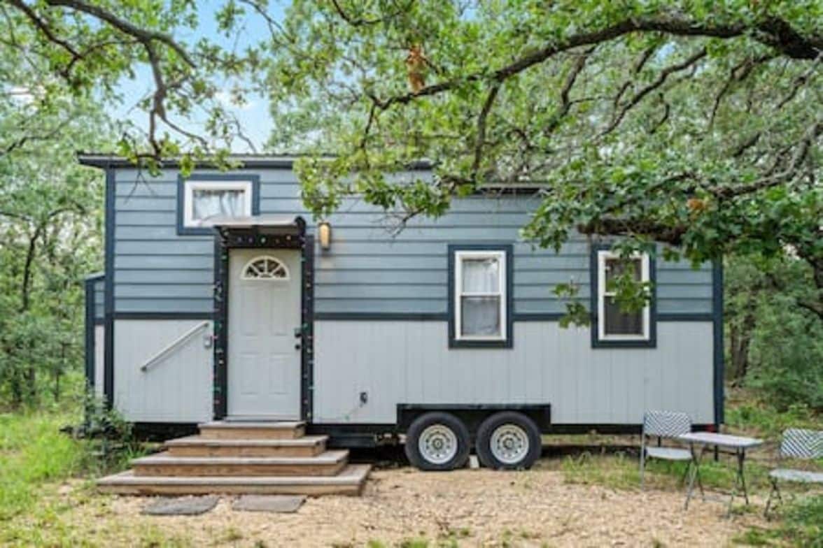 A small, single-story mobile home with a front door, a small porch, and a side window.