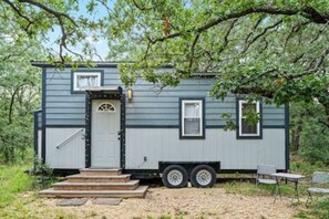 A small, single-story mobile home with a front door, a small porch, and a side window.