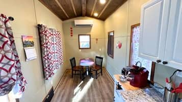 A compact kitchen with a dining area, wooden ceiling, and a small window.