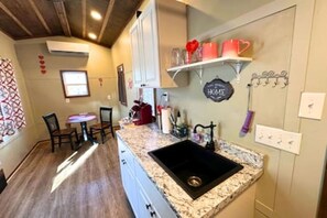 A compact kitchen with a granite countertop, a black sink, and a small dining area with chairs.