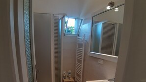 A compact bathroom with a toilet, a sink, and a shower area. - red fountain house (arizzano)