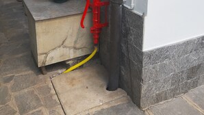 A potted plant with red flowers, a red fire hydrant, and a water pipe on a stone ledge. - red fountain house (arizzano)