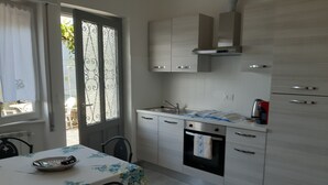 A modern kitchen with a dining area, featuring a table with a floral tablecloth, a built-in oven, and a stainless steel sink. - red fountain house (arizzano)