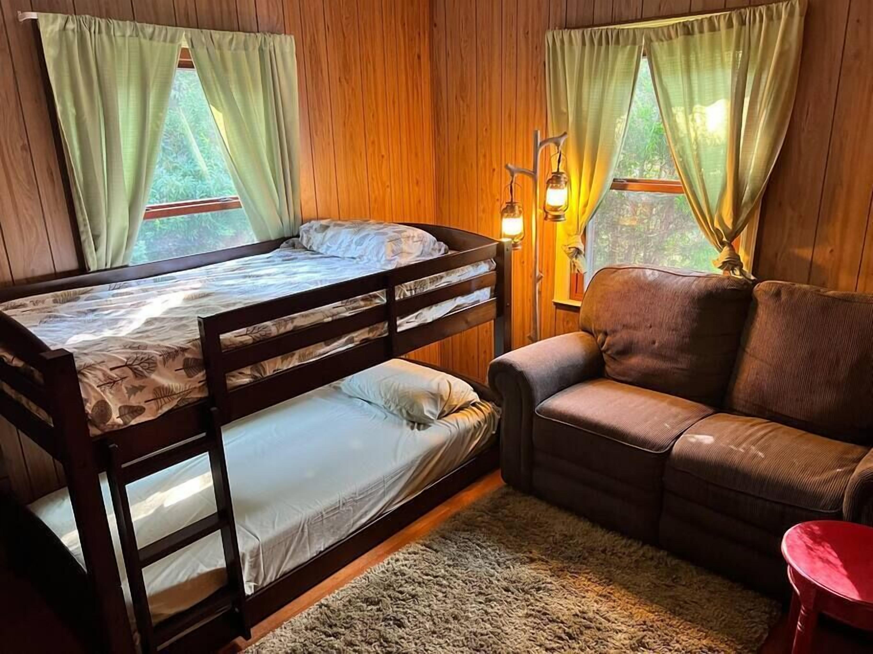 A cozy room with a bunk bed, a sofa, and a small table.