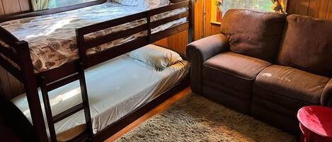 A cozy room with a bunk bed, a sofa, and a small table.