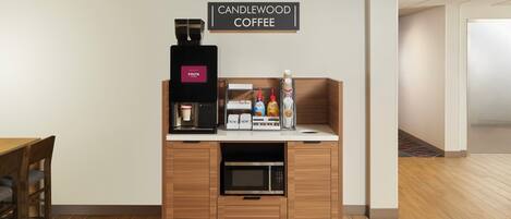 A coffee station with a coffee machine, milk and sugar dispensers, and a sign reading 'CANDLEWOOD COFFEE'.
