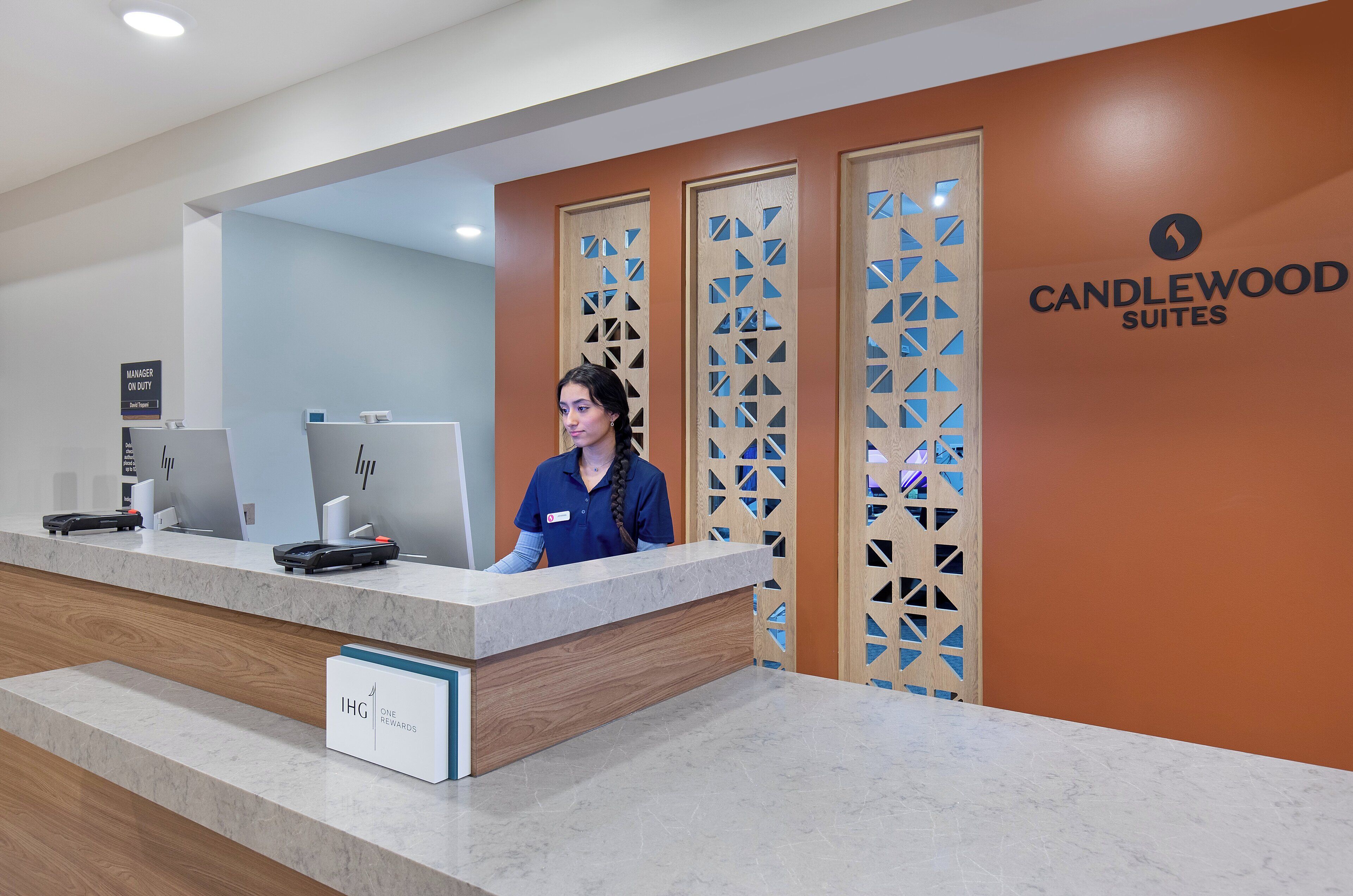 A reception desk with a sign for "IHG ONE REWARDS" and a "MANAGER ON DUTY" sign.