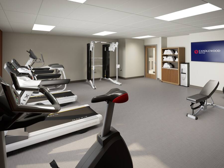 A fitness room with treadmills, a stationary bike, a weight machine, and a chair.