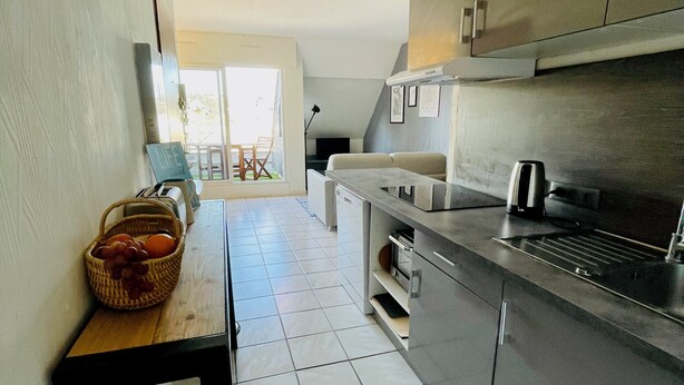 Cozinha moderna com ilha central, eletrodomésticos de aço inoxidável e vista para área externa.