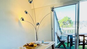 Uma área de refeições com mesa de madeira, bancos e vista para o exterior através de uma porta de vidro.