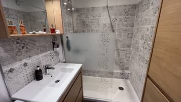 Casa de banho moderna com um espelho grande, duas pias e zona de duche.