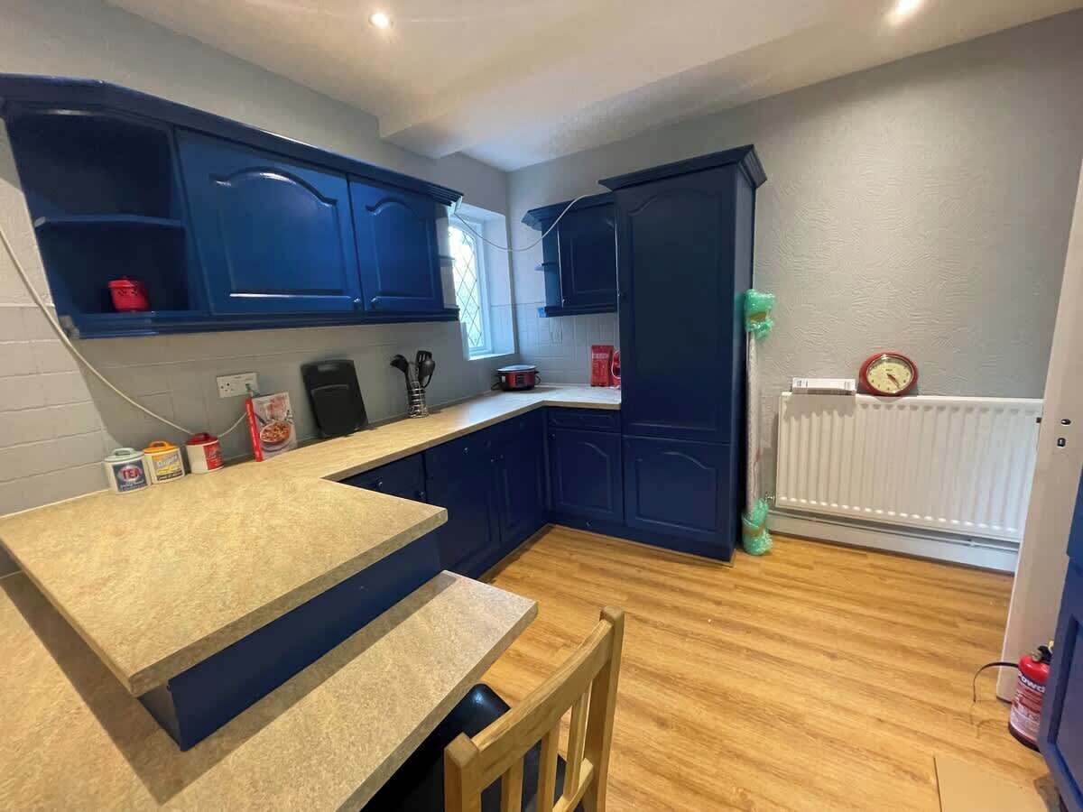A compact kitchen with dark blue cabinets, a wooden countertop, and a small dining area.