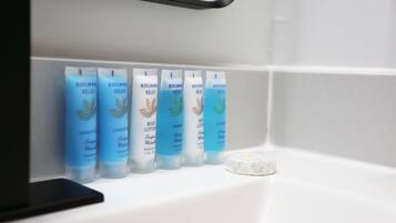 A bathroom shelf with five bottles of Bergman Kelly body lotion and a bar of soap.