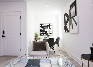 En moderne stue med en sofa, et spisebord med stole og abstrakt kunst p å væggene.