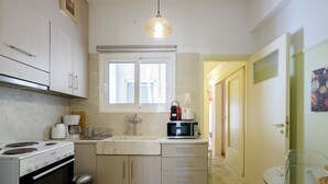 Eine kleine Küche mit Herd, Spüle und Mikrowelle. Über der Spüle befindet sich ein Fenster und eine Tür, die in einen anderen Raum führt.